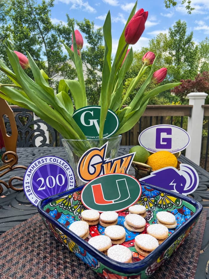 A tray of alfajores surrounded by college decals for a graduation celebration