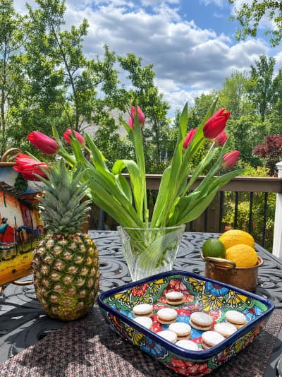 Alfajores on a Peruvian tray outdoors with tulips and pineapple